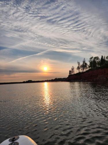 a sunset on a lake with a boat in the water at Waterfront Cottage beach access in Stratford