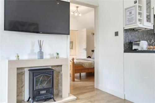 a living room with a fireplace with a tv above it at The Willows in Great Horkesley