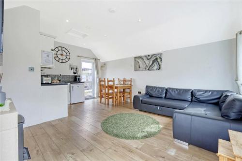 a living room with a blue couch and a kitchen at The Willows in Great Horkesley