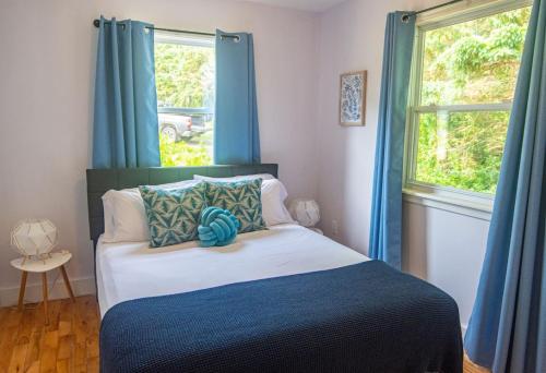 a bedroom with a bed with blue curtains and a window at Waterfront Cottage beach access in Stratford