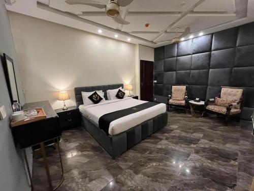 a bedroom with a bed and chairs in a room at Palm tree suites in Lahore