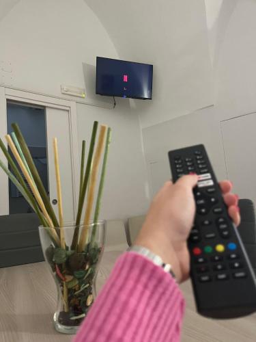 a person holding a remote control in front of a table at Lips House in Gravina in Puglia