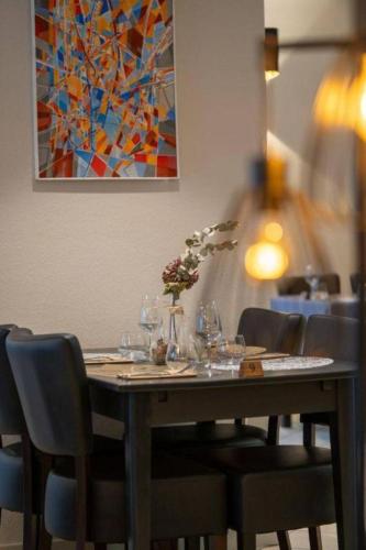 a table in a restaurant with chairs and a painting at Hôtel Restaurant Le Madame in La Ferrière