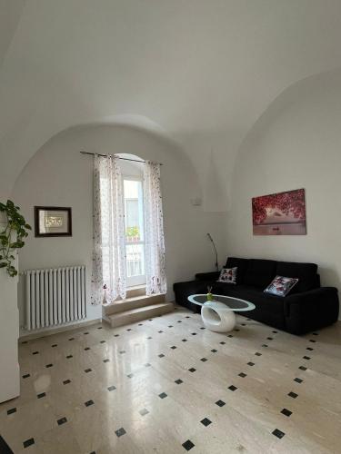 a living room with a black couch and a window at Lips House in Gravina in Puglia
