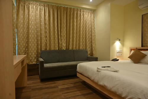 a bedroom with a bed and a couch and a window at Golden Square - Kolkata Airport in Kolkata