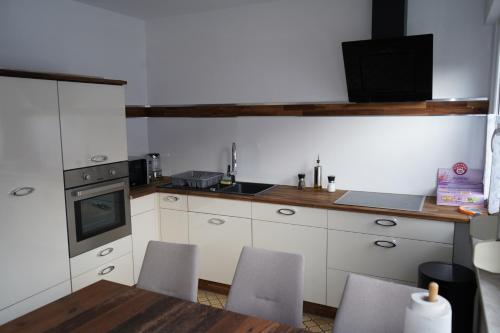 バート・ハルツブルクにあるFeWo DT ''Bismarck'' mit traumhafter Balkonaussichtの白いキャビネットとテーブルと椅子のあるキッチン