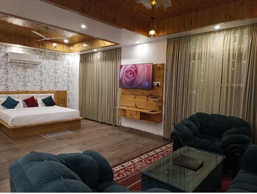 a bedroom with a bed and a couch and a tv at The Crown in Dharamshala