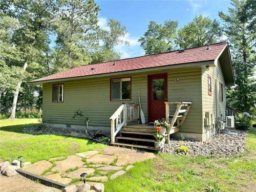 a small green house with a red door at Cute Whitefish Cabin with Hot tub in Cross Lake