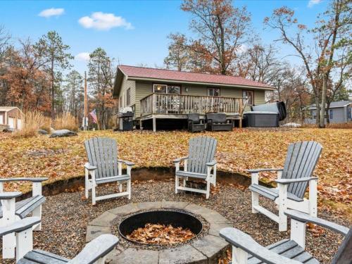 three chairs sitting around a fire pit in front of a house at Cute Whitefish Cabin with Hot tub in Cross Lake
