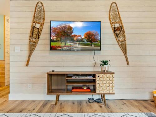 a living room with a tv on a white wall at Cute Whitefish Cabin with Hot tub in Cross Lake