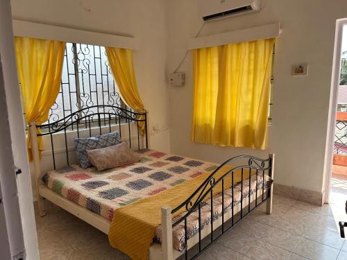 a bedroom with a bed with yellow curtains and a window at Kepler Executive Apartment by AT Hotel Collection in Colva