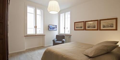 a bedroom with a bed and a chair and windows at Palazzo Dalla Rosa Prati in Parma