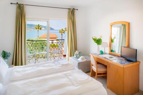 a bedroom with a bed and a desk with a mirror at Hotel Moresco in Diano Marina