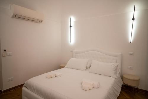 a white bed with white pillows and towels on it at Enjoyhousebracciano suite2 in Bracciano