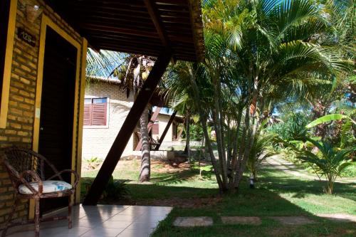 a porch of a house with a chair and palm trees at Pousada Império do Sol in Pipa