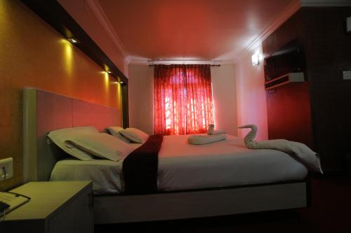 a bedroom with two beds and a window with two swans at City Palace Hotel in Ooty