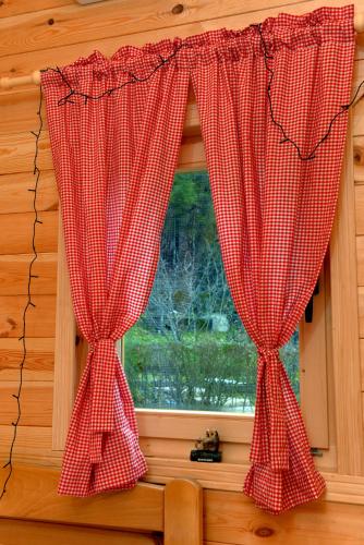 a window with red checkered curtains in a room at Vojinov kutak in Mojkovac
