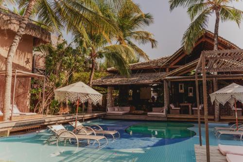 a pool with chairs and umbrellas next to a house at Aloha Village Hotel in Icaraí
