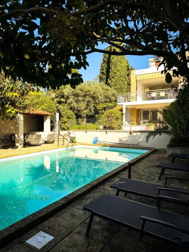 une piscine avec des chaises et un bâtiment dans l'établissement Villa NAIO - Piscine privée - Parking - Climatisation, à Cassis