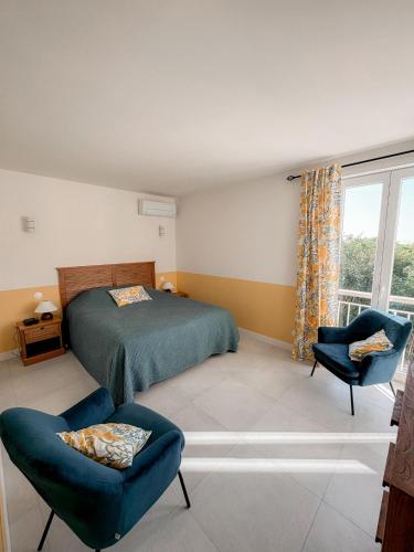 une chambre avec un lit et deux chaises et une fenêtre dans l'établissement Villa NAIO - Piscine privée - Parking - Climatisation, à Cassis