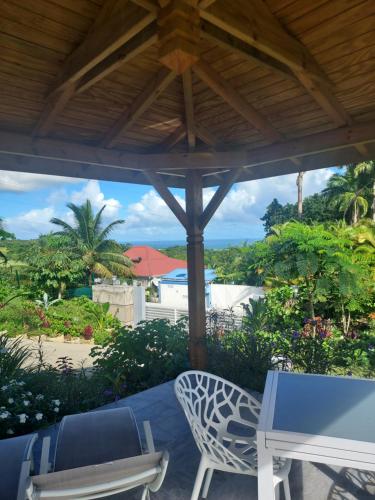 a patio with a table and chairs and a view of the ocean at LE PETIT PARADIS in Sainte-Rose