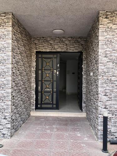 リヤドにあるSmart Entry Room Al-Narjis 2の黒い扉とレンガの壁の廊下