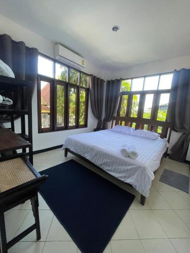 a bedroom with a bed and some windows at Villa Aisawan in Phuket