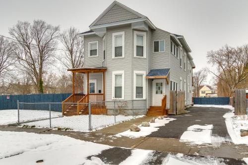 a white house with a fence in the snow at 2 Mi to Syracuse University Apt with Fire Pit in Syracuse