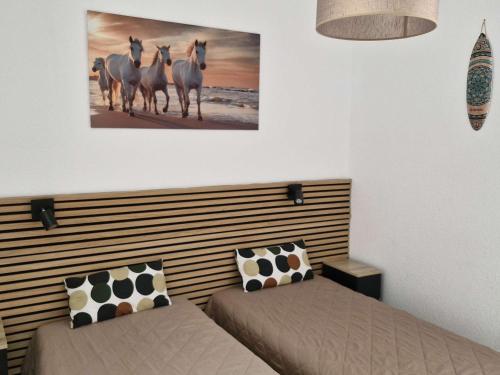 Cette chambre comprend 2 lits et une photo de chevaux sur le mur. dans l'établissement Appartement Climatisé avec Terrasse et Piscine au Lavandou - FR-1-308-168, au Lavandou