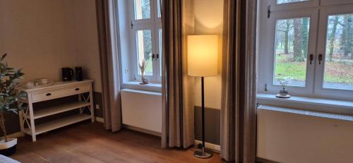 a room with two windows and a lamp and a table at Schlosshotel Hohenbocka in Hohenbocka