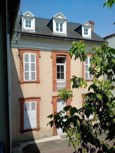 un bâtiment avec des portes et des fenêtres blanches sur une rue dans l'établissement Studio Gare SNCF, à Tarbes