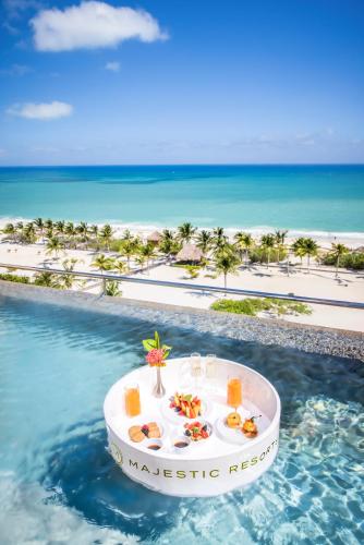 a tray of food on a table in the water next to the beach at Majestic Elegance Costa Mujeres - All Inclusive in Cancún