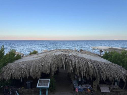 a large straw umbrella on the beach near the water at Amanda beach hotel in Dahab