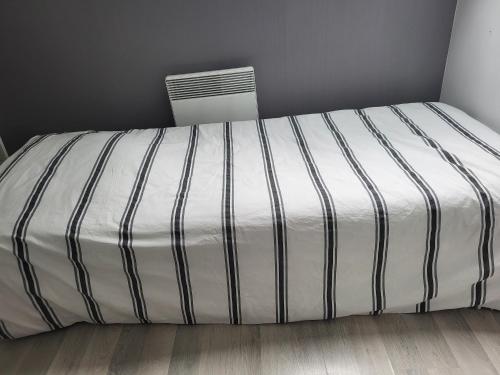 ein Bett mit einer schwarzen und weißen Bettdecke in einem Zimmer in der Unterkunft Grande maison jusqu'à 9 pers in Ézy-sur-Eure