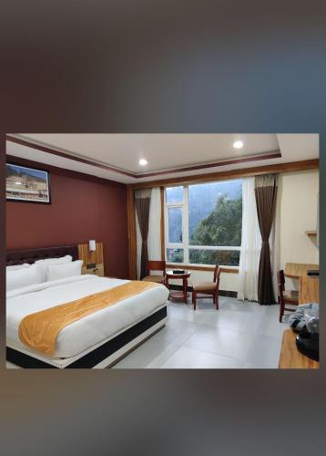 a bedroom with a large bed and a large window at Kanchejunga Mountain view resort in Gangtok