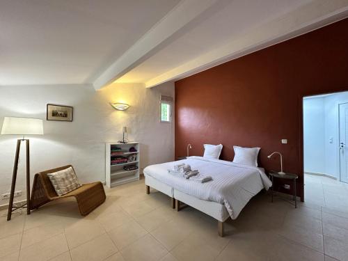 une chambre avec un grand lit et une chaise dans l'établissement Villa Les Romarins pour 8 personnes avec vue mer panoramique et piscine chauffée à La Londe-les-Maures, à La Londe-les-Maures