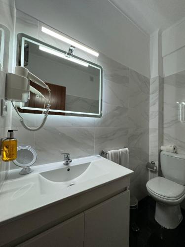 a bathroom with a sink and a toilet and a mirror at Hotel Onix in Viseu