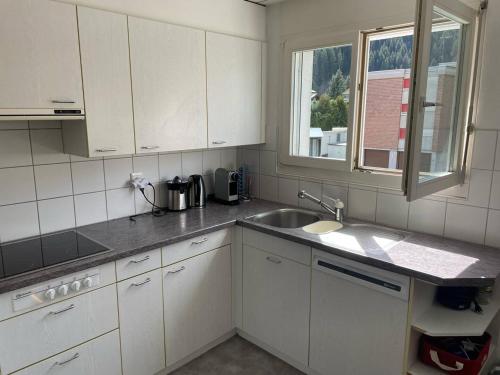 a kitchen with white cabinets and a sink and a window at Superspot Ferienwohnung mit Super Aussicht in Churwalden