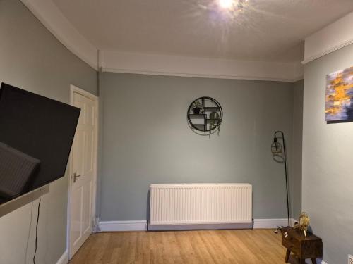 an empty living room with a radiator and a tv at The Reddish Retreat in Manchester