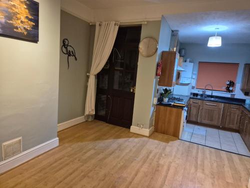 an empty living room with a kitchen and a door at The Reddish Retreat in Manchester