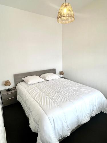 une chambre avec un grand lit blanc avec un lustre dans l'établissement Appartement calme avec exterieur, à Aytré