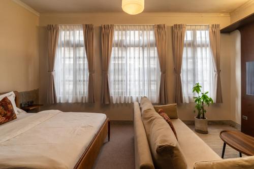 a bedroom with a bed and a couch and windows at 安樓文旅 Enzo House in Keelung