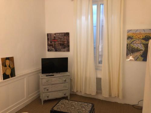 Cette chambre dispose d'une télévision sur une commode et d'une fenêtre. dans l'établissement Le Victor HUGO 1G et sa pizza offerte, à Aurillac
