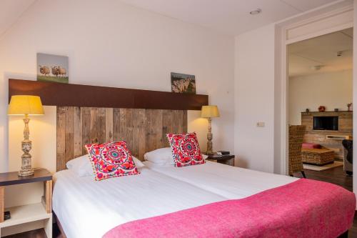 a bedroom with a large white bed with red pillows at Hotel De Walvisvaarder in Lies