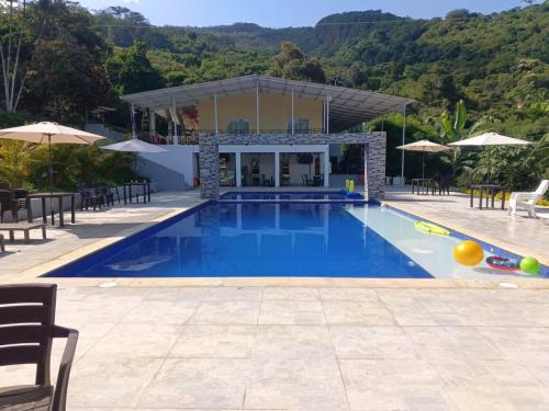 a large swimming pool with chairs and umbrellas at Finca Villa Carmen, Vía Magdalena in Villeta