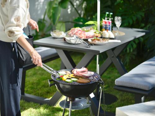 a woman is cooking food on a grill at Chura Kouri in Nakijin