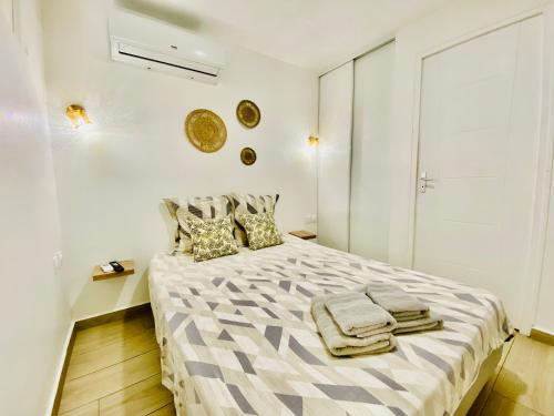 a white bedroom with a bed with towels on it at Sun7 appart T2, avec piscine partagée, logement moderne et cosy in Petit-Bourg
