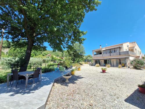 un patio avec une table et des chaises devant un bâtiment dans l'établissement Association Vita'vie La Villa, à Peyruis