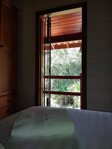 a bedroom with a bed and a window with a blind at Chalé da Ana in Santo Antônio do Pinhal