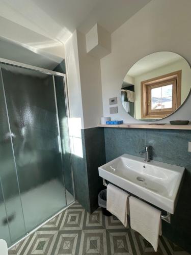 a bathroom with a shower and a sink and a mirror at Garni La Casetta in Livigno